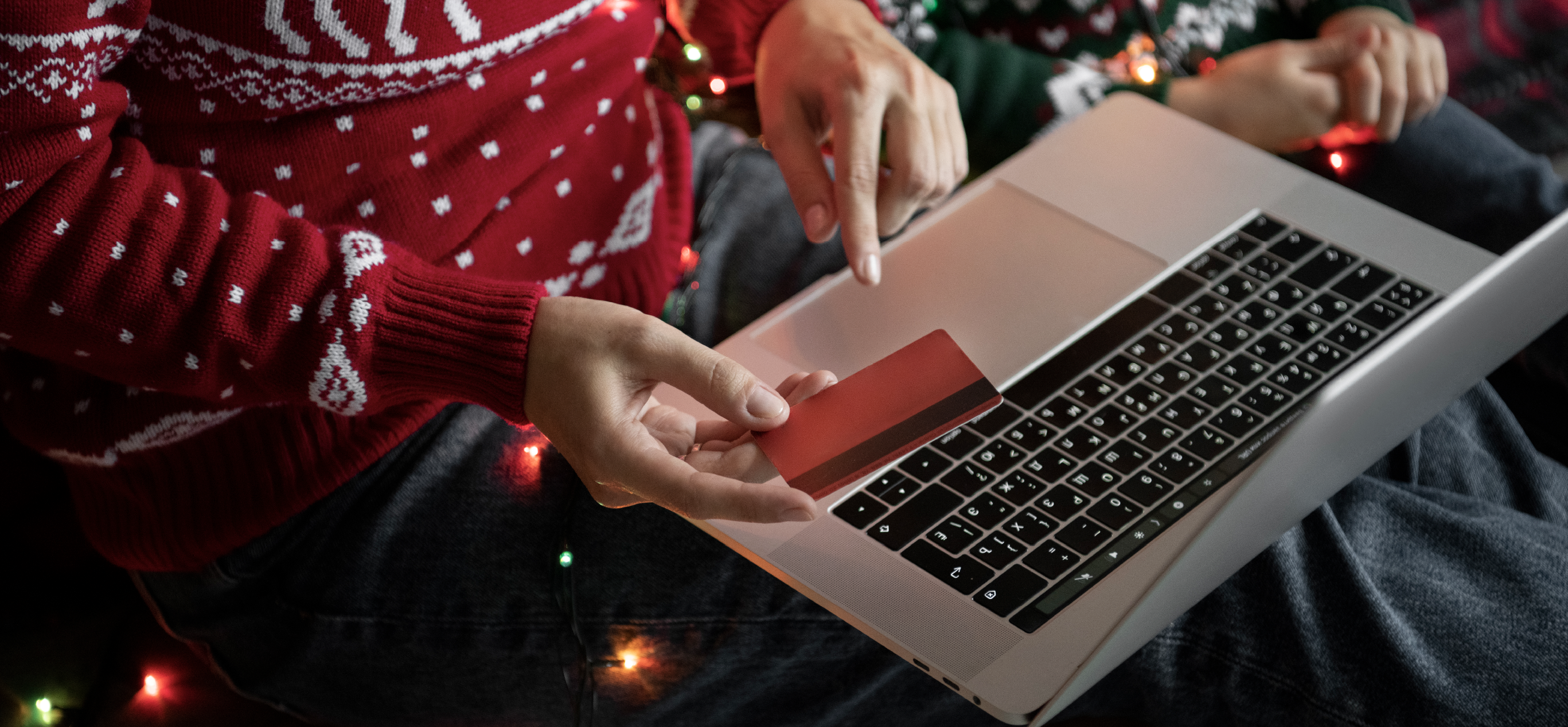 Personne en train de tenir sa carte de crédit devant son ordinateur pour acheter sur un site e-commerce